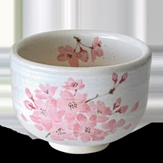 a white bowl with pink flowers painted on the outside and inside, in front of a white background