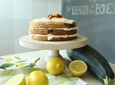 a cake sitting on top of a table next to lemons and zucchini