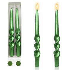 green candles are sitting in a box next to two smaller candles with one candle lit