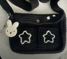 a crocheted black purse with white stars and a bunny on the front pocket