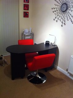 a black table with two red chairs and a clock on the wall