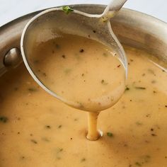 a ladle pouring gravy into a pot filled with soup