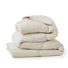 a pile of white pillows and blankets on top of each other, with the covers folded down