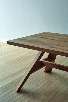 a wooden table sitting on top of a hard wood floor next to a white wall