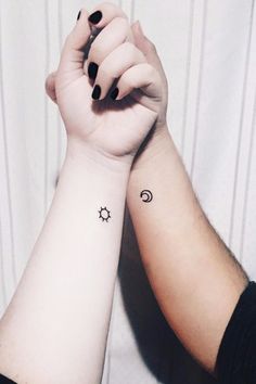 two people holding hands with tattoos on their arms and one has a sun and moon