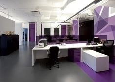 an office with purple and white decor on the walls, desks and chairs in front of it