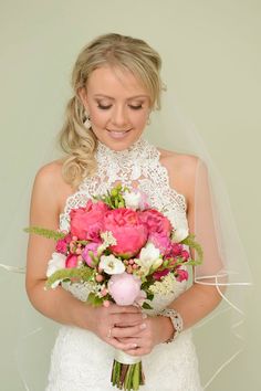 a bride holding a bouquet of pink and white flowers