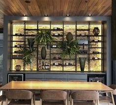 a dining room table and chairs with plants on the wall behind it in front of a bookcase