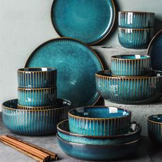 a table topped with lots of blue dishes and bowls next to chopsticks on top of a counter