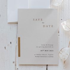 a wedding save the date card on top of a white envelope with gold foiling