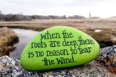 a green rock with a poem written on it sitting on top of a rocky outcropping