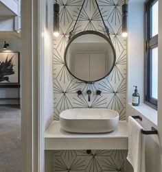 a white sink sitting under a round mirror next to a wall mounted faucet