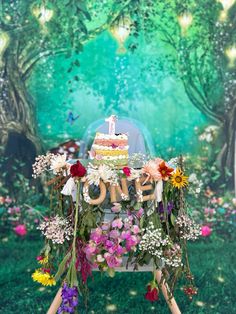 a birthday cake sitting on top of a wooden sign surrounded by flowers and greenery