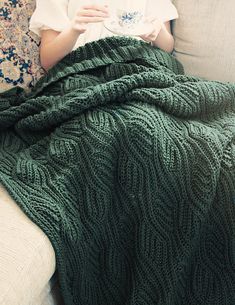 a woman sitting on a couch holding a cup