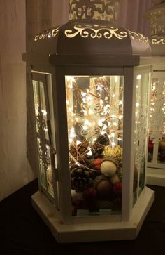 a lighted lantern with christmas decorations in it