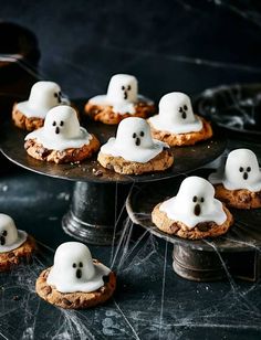 some cookies with white icing and ghost faces on them are sitting on a table