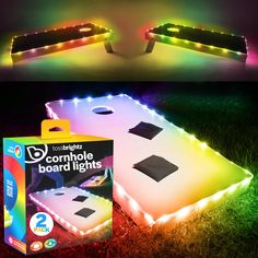 two light up cornhole boards in the grass, one with lights on top and one with