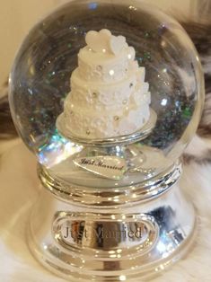 a snow globe with a wedding cake in it sitting on top of a fur rug