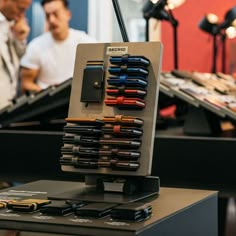 there are many different types of pens in this display case and two men looking at them