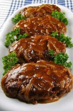 three pieces of meat covered in gravy on a white plate