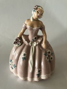 a ceramic figurine of a woman in a pink dress with flowers on it