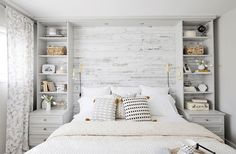 a bed with white linens and pillows in a bedroom next to a book shelf