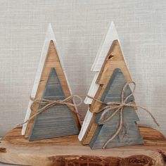 two wooden christmas trees are sitting on a piece of wood