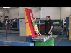 a man standing next to a child on top of a trampoline in a gym