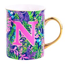 a colorful mug with the letter n on it's side and tropical leaves surrounding it