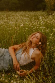 a woman laying in the grass with her eyes closed and head tilted to the side