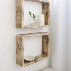 two wooden shelves with candles and vases on them in the corner of a bathroom