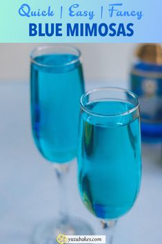 two glasses filled with blue mimosas sitting on top of a table