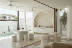 a living room filled with white furniture next to a swimming pool