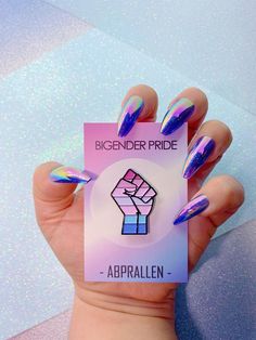 a person holding up a sticker with purple and blue nails