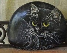 a painted rock with a black cat on it