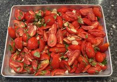 a metal pan filled with lots of tomatoes and almonds on top of a counter