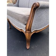 an antique style couch with grey upholstered fabric and wood trimmings on the arms