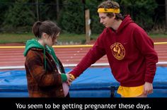 a man and woman standing next to each other on a track with a blue tarp behind them