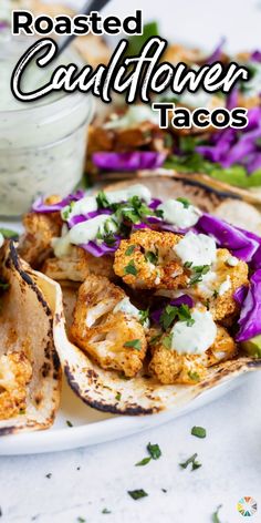 roasted cauliflower tacos on a plate with purple cabbage and sour cream in the background