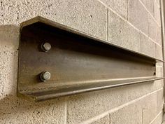 a metal object mounted to the side of a building on a brick wall with rivets