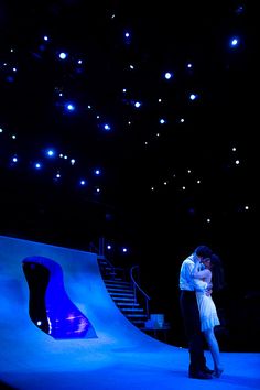 a man and woman standing in front of a stage with blue lights on the ceiling