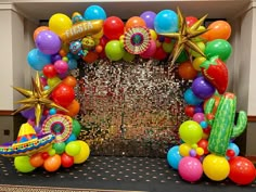 balloons and streamers decorate the entrance to a party with an arch that reads fiesta