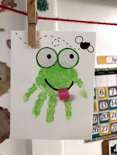 a green hand print hanging from a clothes line with magnets attached to the clothesline