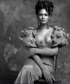 a black and white photo of a woman in a dress with roses on her shoulders