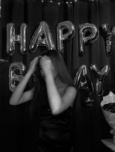 a woman standing in front of balloons that say happy birthday