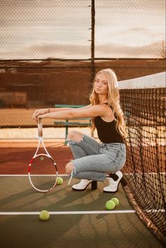 a beautiful young woman holding a tennis racquet on top of a tennis court