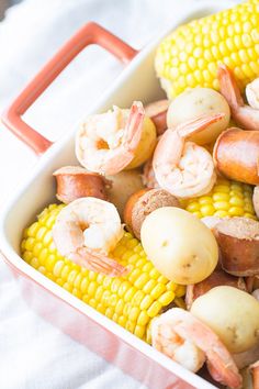 shrimp, corn on the cob and potatoes in a white casserole dish