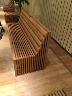 a wooden bench sitting on top of a hard wood floor next to a planter