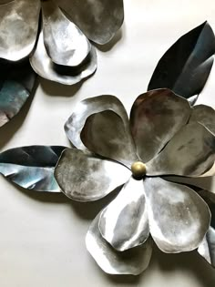 two metal flowers on a white surface with one flower in the center and another flower in the middle