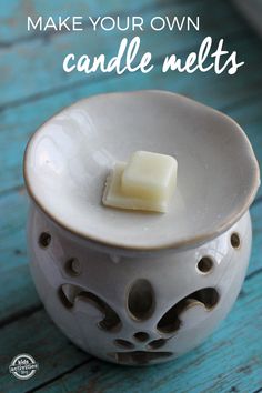 a white candle holder sitting on top of a blue wooden table with text overlay that reads make your own candle melts